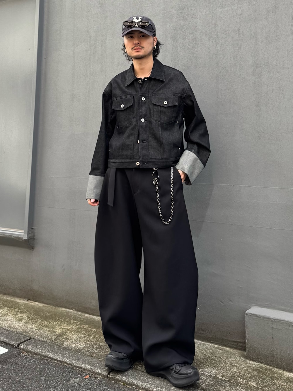 ブラック系のデニムジャケット、ブラック系のスラックス、ブラック系のウォレットチェーンを着用したメンズの春コーディネートの1枚目の写真