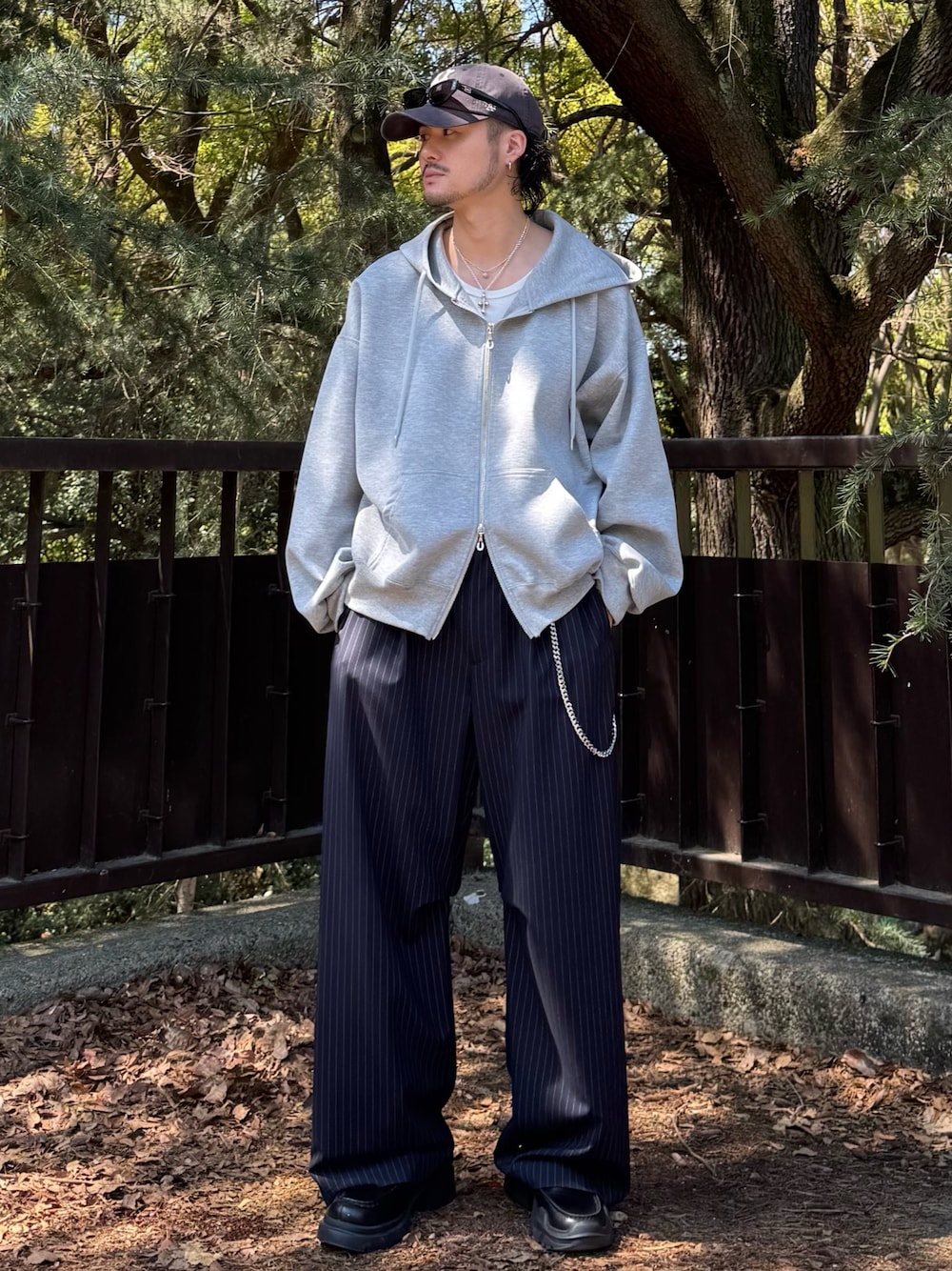 グレー系のパーカー、ブルー系のスラックス、シルバー系のウォレットチェーンを着用したメンズの春コーディネートの1枚目の写真