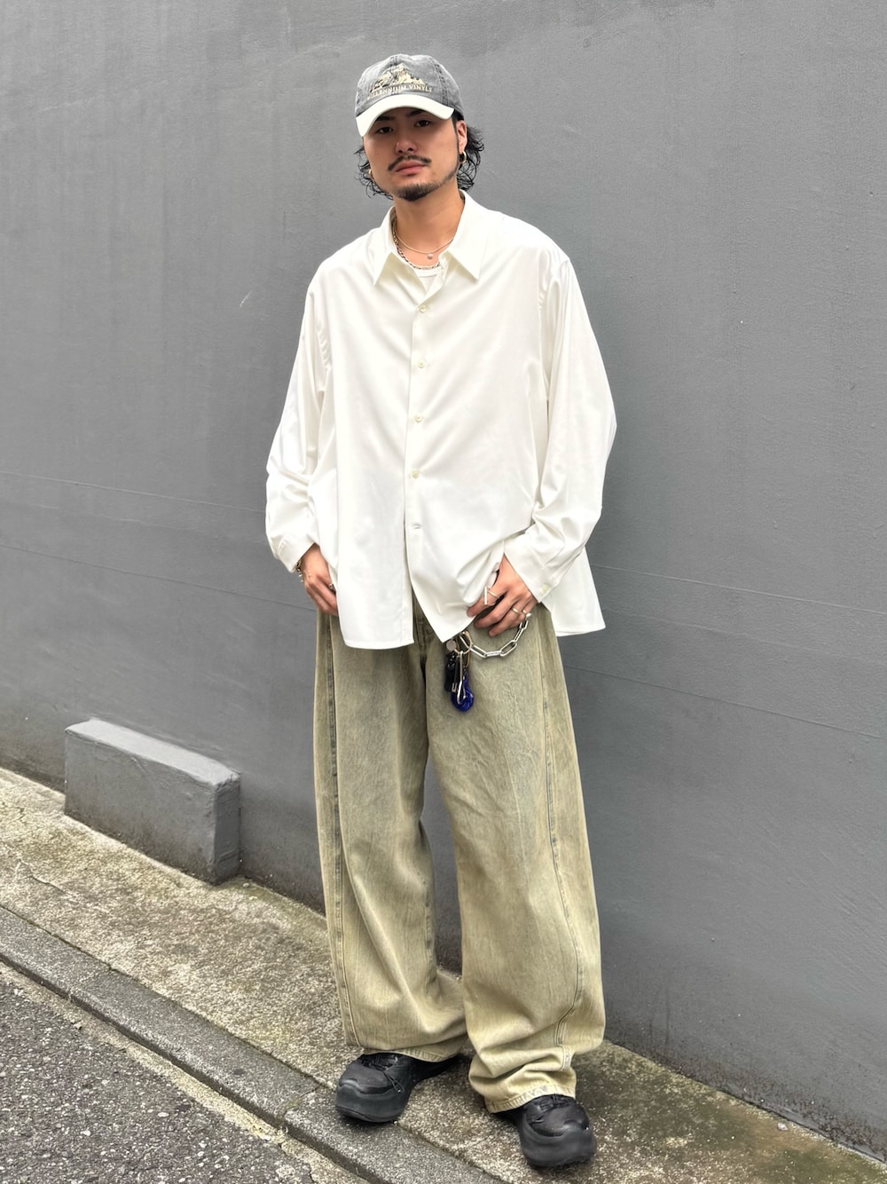 ホワイト系のトップス、グリーン系のデニムパンツを着用したメンズの夏コーディネートの1枚目の写真