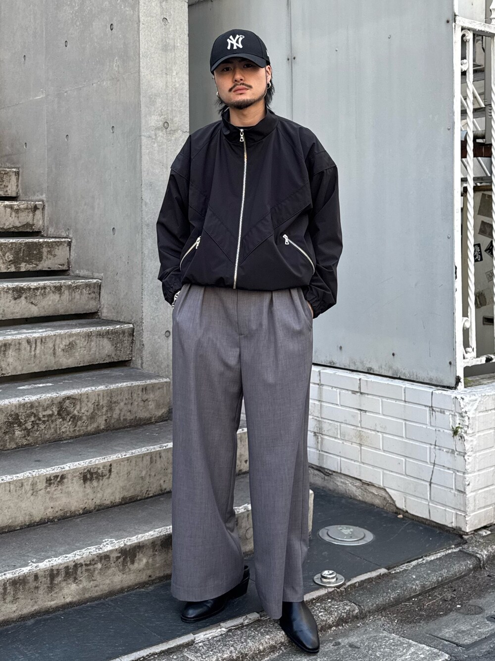 グレー系のスラックス、ブラック系のブルゾン、ブラック系のその他シューズを着用したメンズの春コーディネートの1枚目の写真