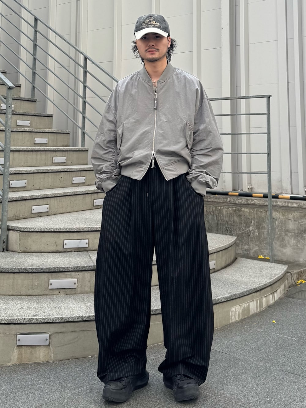グレー系のMA-1、ブラック系のスラックスを着用したメンズの春コーディネートの1枚目の写真