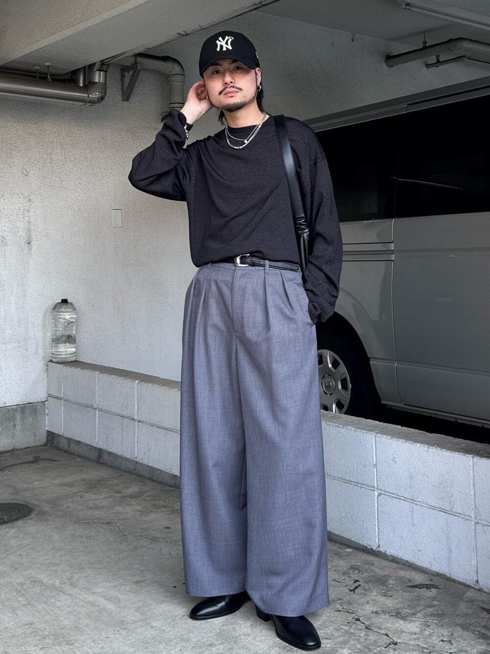 ブラック系のニット/セーター、グレー系のスラックス、ブラック系のショルダーバッグを着用したメンズの春コーディネートの1枚目の写真