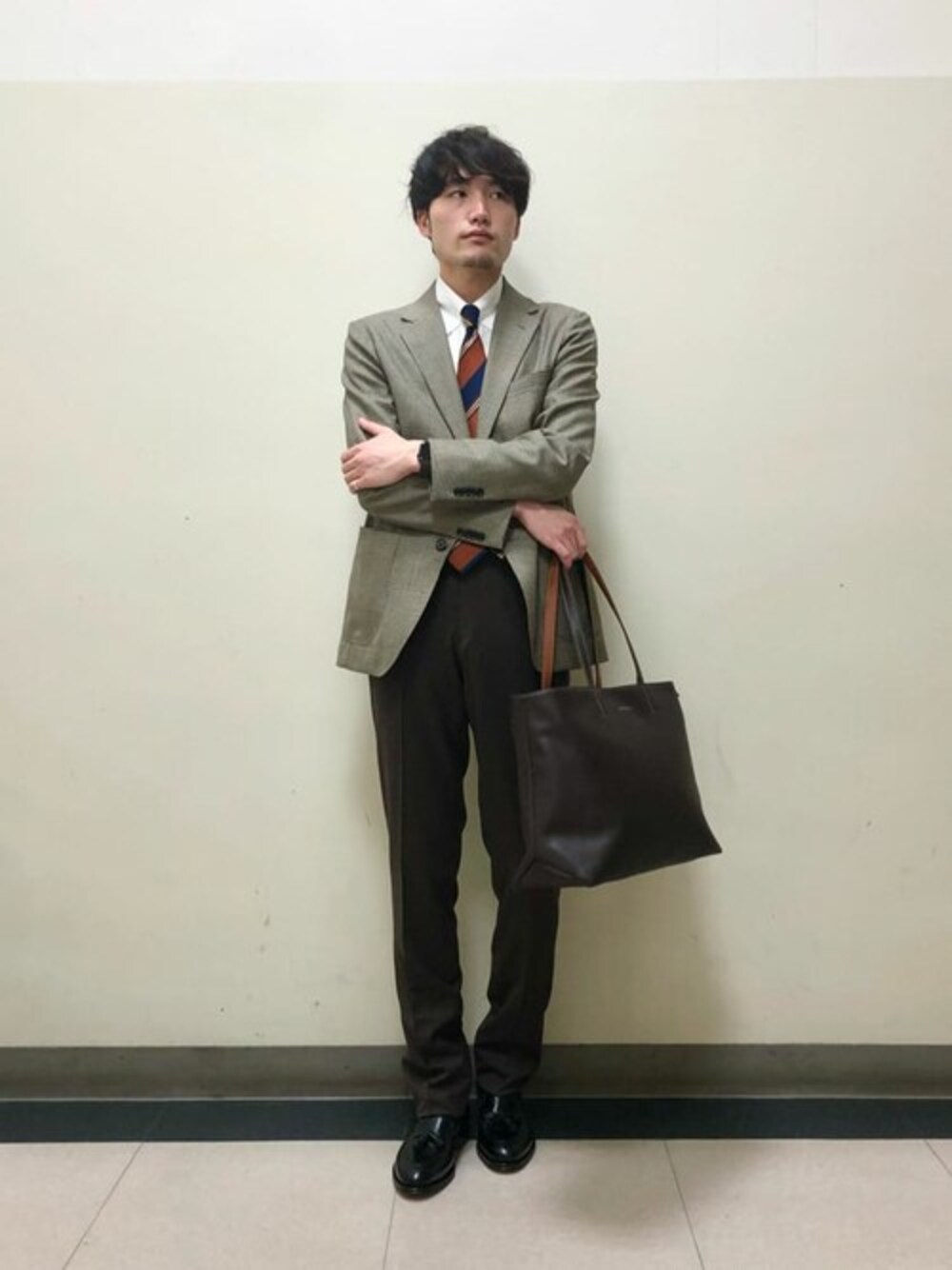 ベージュ系のテーラードジャケット、ホワイト系のビジネスシャツ、ブラウン系のスラックスを着用したメンズの秋コーディネートの1枚目の写真