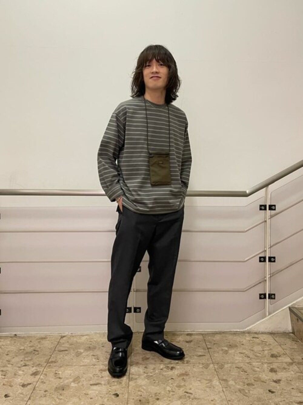 グリーン系のTシャツ/カットソー、ブラウン系のチノパンツ、ブラック系のローファーを着用したメンズの秋コーディネートの1枚目の写真