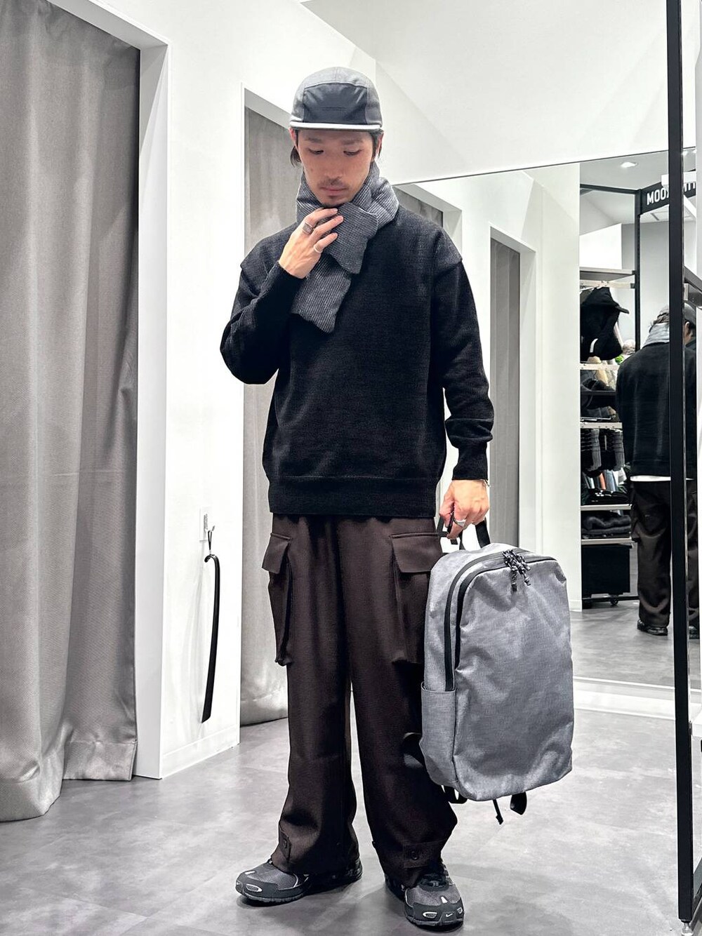 ブラック系のニット/セーター、グレー系のバックパック/リュック、ブラウン系のカーゴパンツを着用したメンズの秋コーディネートの1枚目の写真
