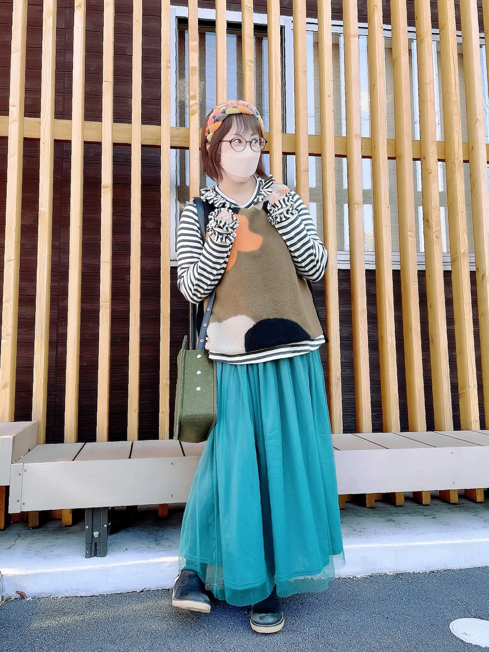 ブラック系のトップス、グリーン系のベスト、グリーン系のショルダーバッグを着用したレディースの秋コーディネートの1枚目の写真