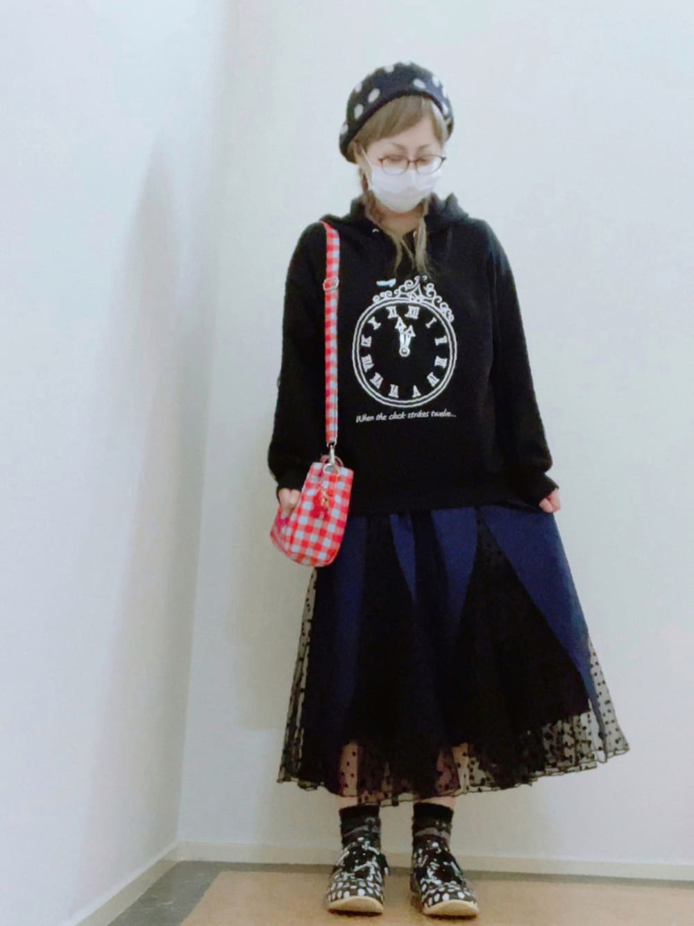 ブラック系のパーカー、ブルー系のショルダーバッグ、ブルー系のスカートを着用したレディースの冬コーディネートの1枚目の写真