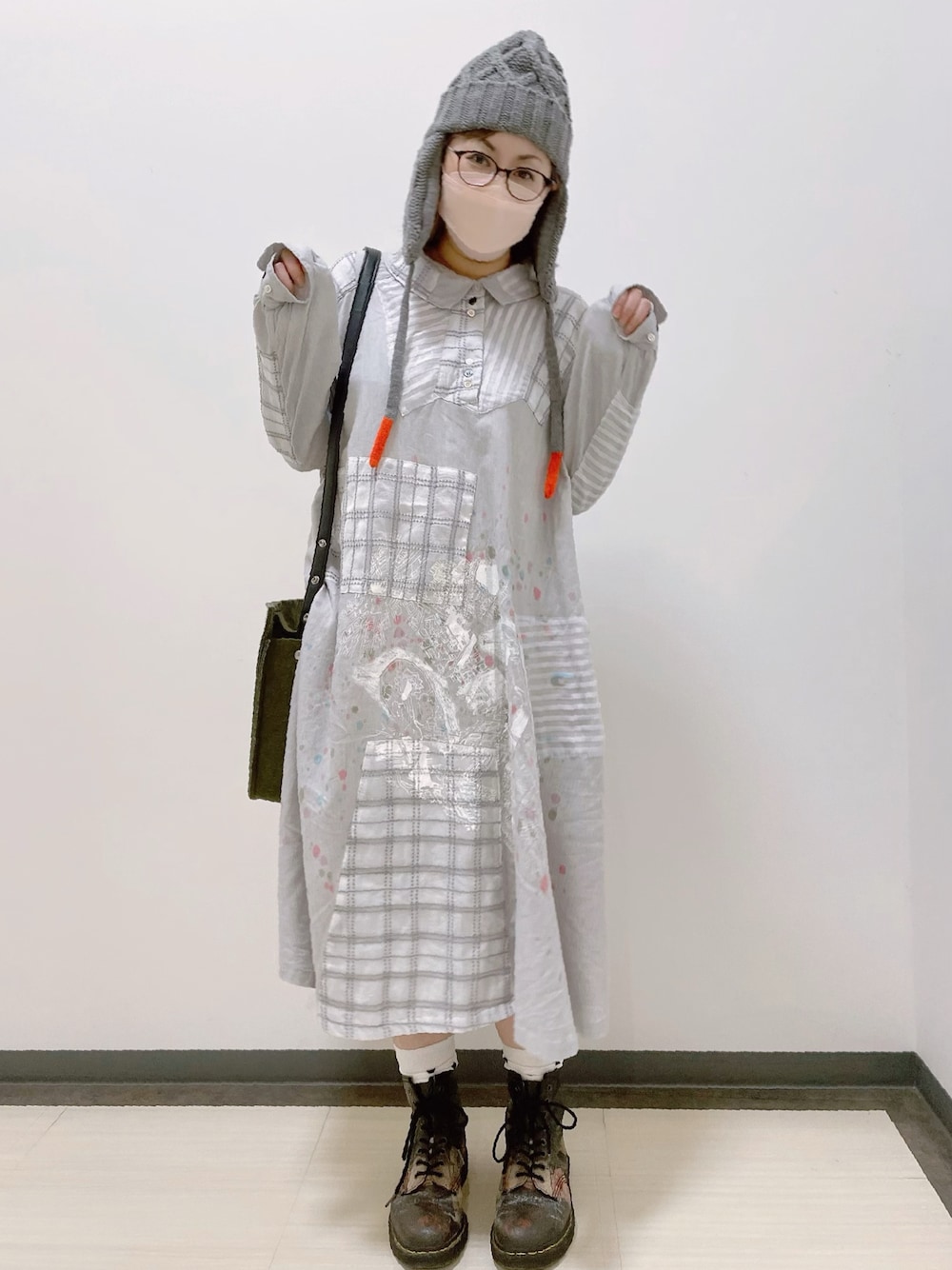 グレー系のワンピース、グリーン系のショルダーバッグ、ブラック系のブーツを着用したレディースの秋コーディネートの1枚目の写真