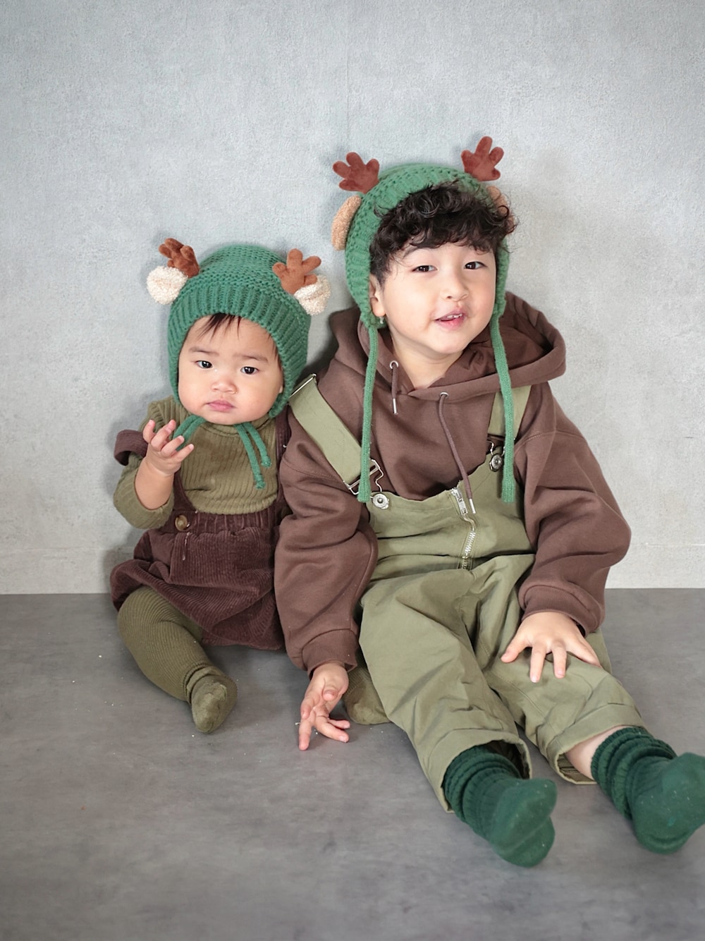 グリーン系のサロペット/オーバーオール、ブラウン系のパーカー、グリーン系のソックス/靴下を着用したキッズの冬コーディネートの1枚目の写真