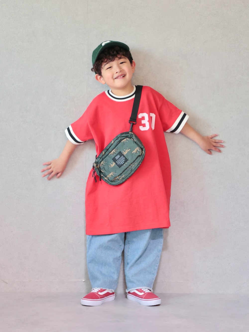 レッド系のワンピース、ブルー系のデニムパンツ、レッド系のスニーカーを着用したキッズの春コーディネートの1枚目の写真