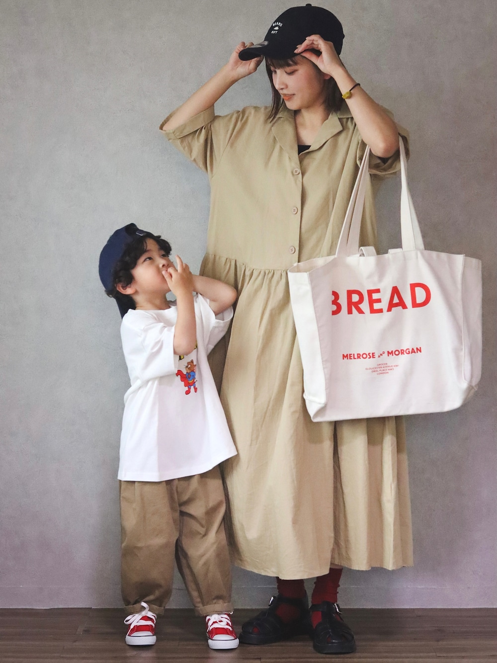 ベージュ系のワンピース、ブラック系のサンダル、ホワイト系のTシャツ/カットソーを着用したキッズの春コーディネートの1枚目の写真