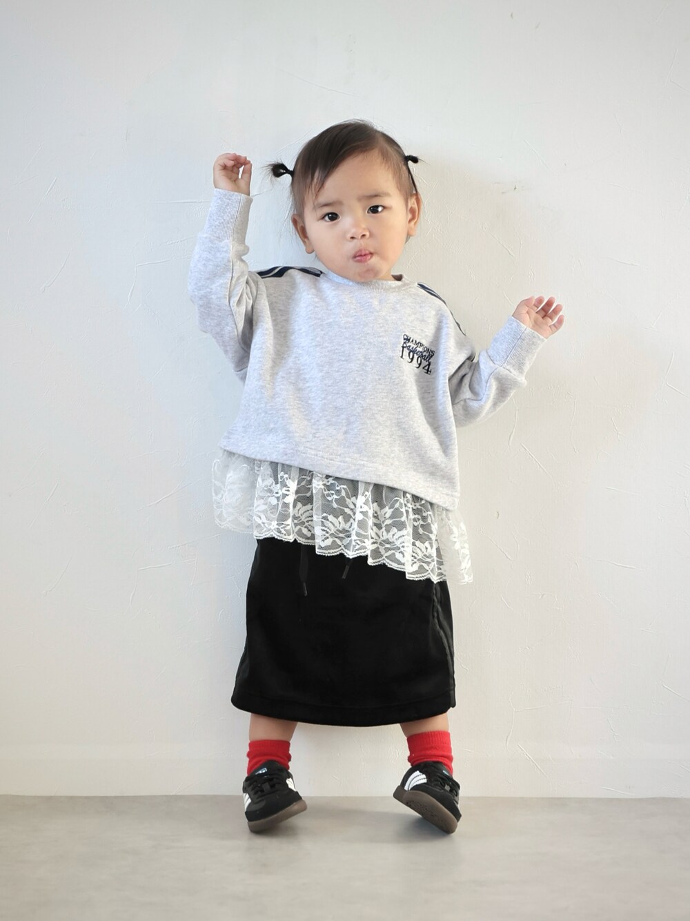 グレー系のスウェット、ブラック系のスカート、ブラック系のスニーカーを着用したキッズの秋コーディネートの1枚目の写真