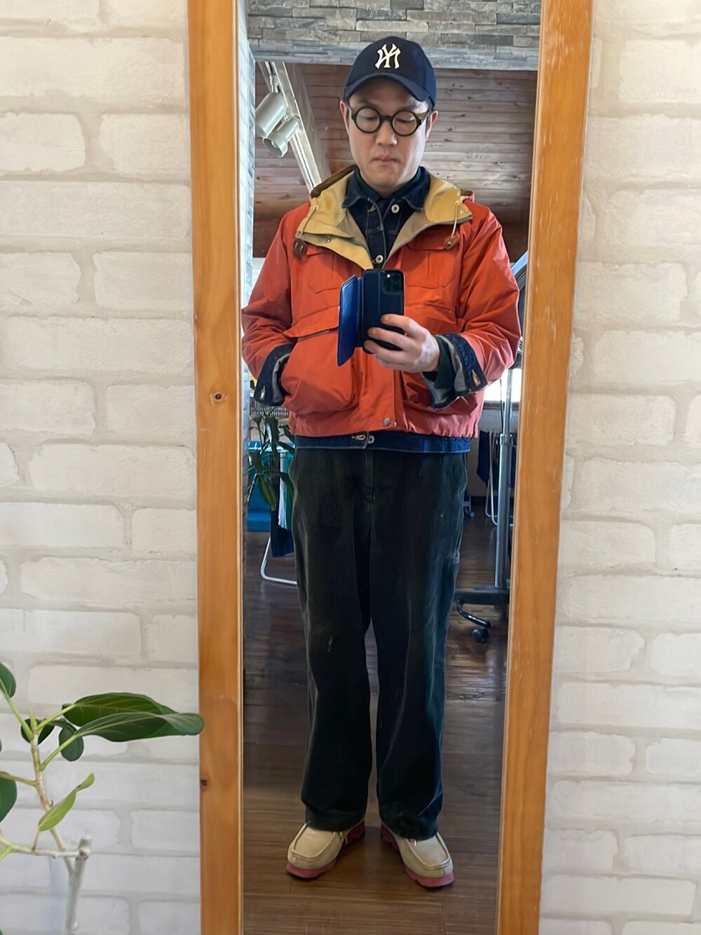 オレンジ系のマウンテンパーカー、グリーン系のその他パンツ、ベージュ系のモカシン/デッキシューズを着用したメンズの春コーディネートの1枚目の写真