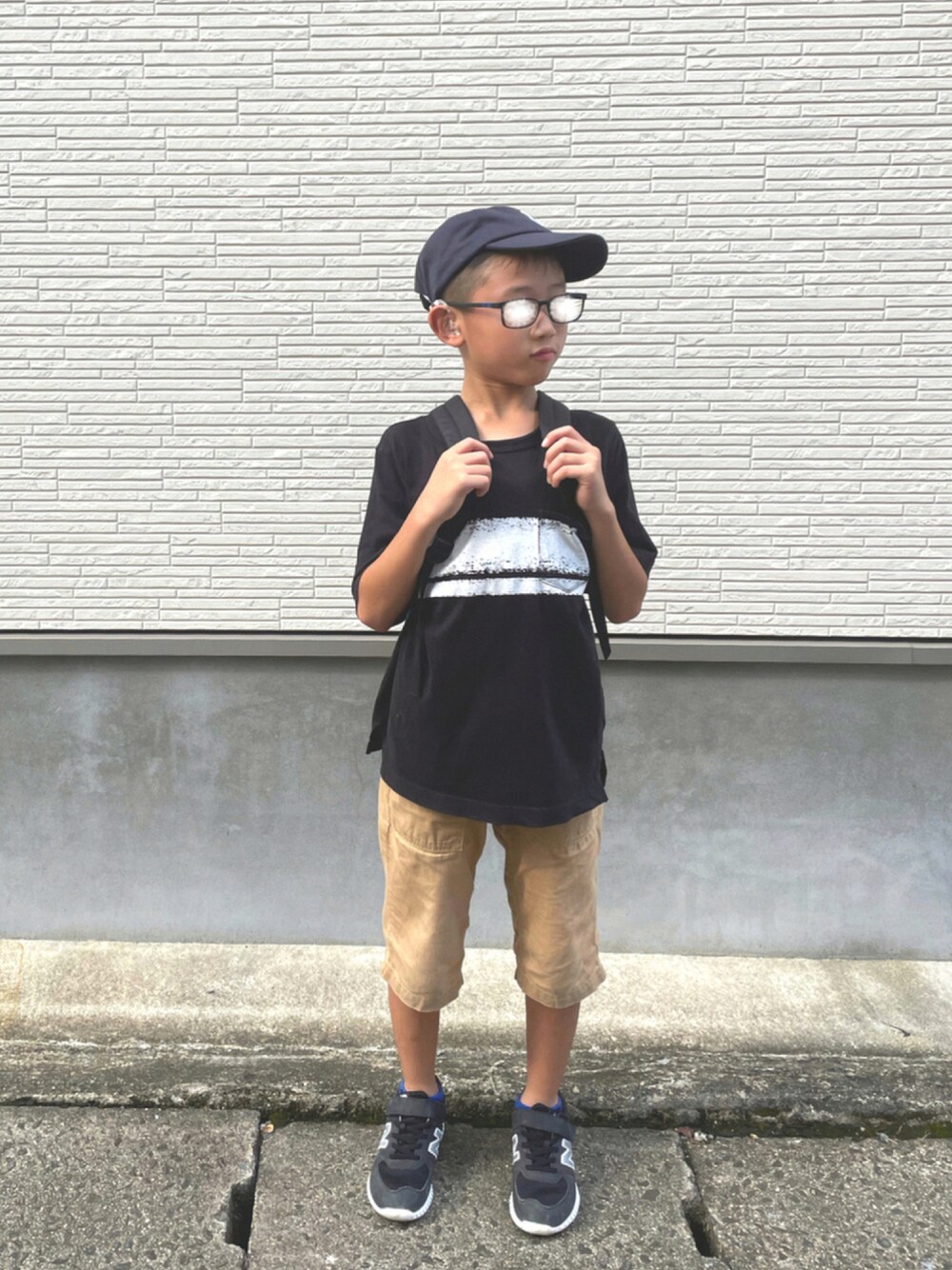 ブラック系のTシャツ/カットソー、ベージュ系のパンツ、ブラック系のスニーカーを着用したキッズの秋コーディネートの1枚目の写真
