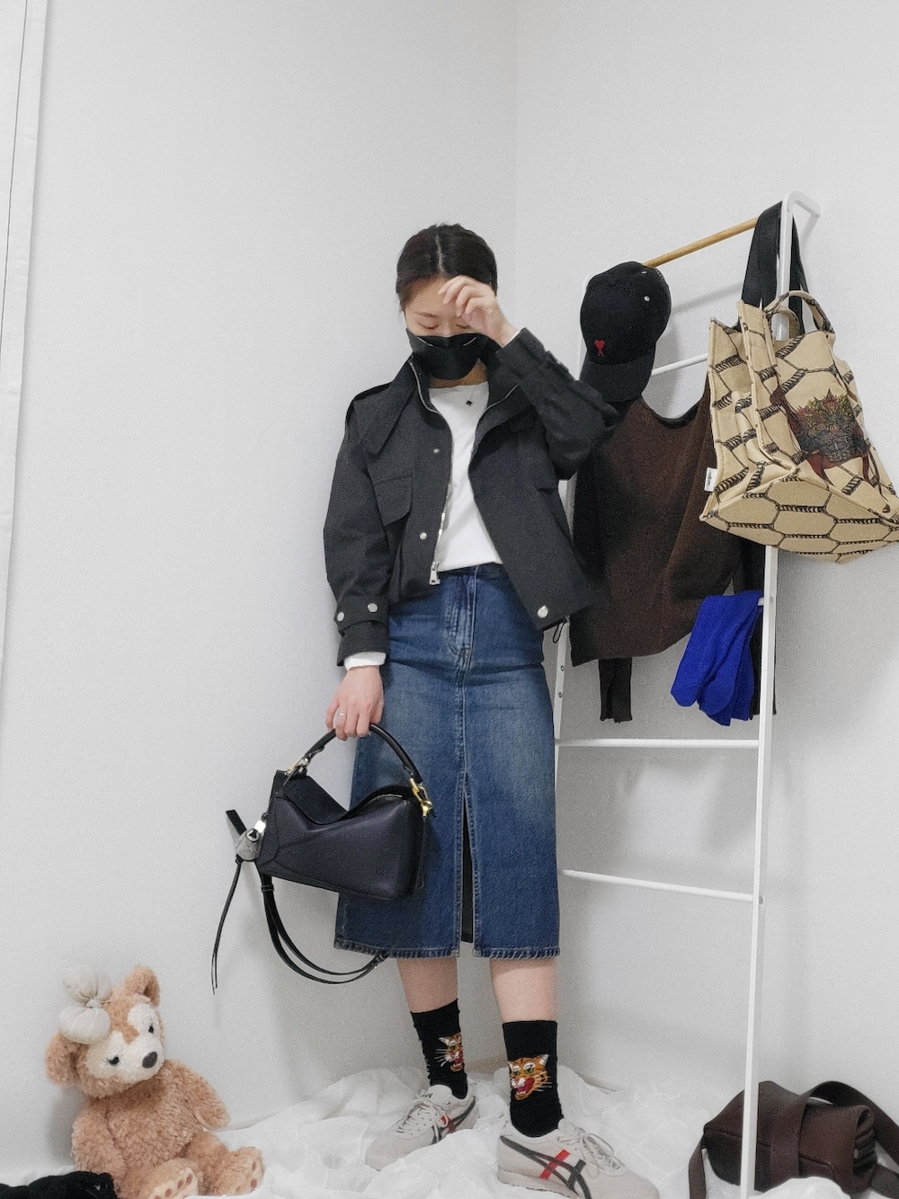 ブルー系のハンドバッグ、ブルー系のデニムスカート、ベージュ系のスニーカーを着用したレディースの春コーディネートの2枚目の写真