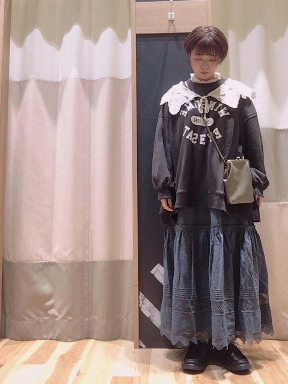 グリーン系のショルダーバッグ、グレー系のスカート、ブラック系のその他シューズを着用したレディースの秋コーディネートの1枚目の写真