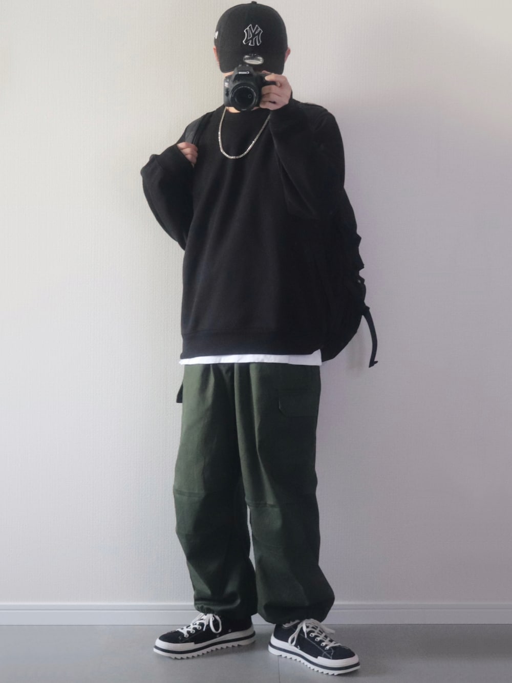 ブラック系のスウェット、ホワイト系のTシャツ/カットソー、グリーン系のカーゴパンツを着用したメンズの秋コーディネートの1枚目の写真