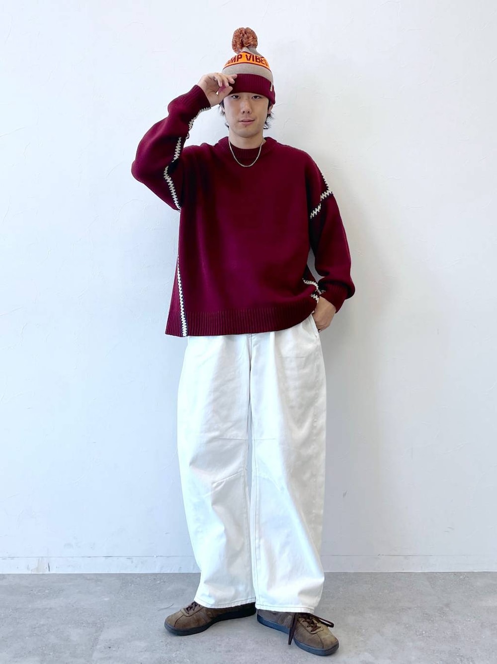 レッド系のニット/セーター、ホワイト系のデニムパンツ、グレー系のニットキャップ/ビーニーを着用したメンズの秋コーディネートの1枚目の写真