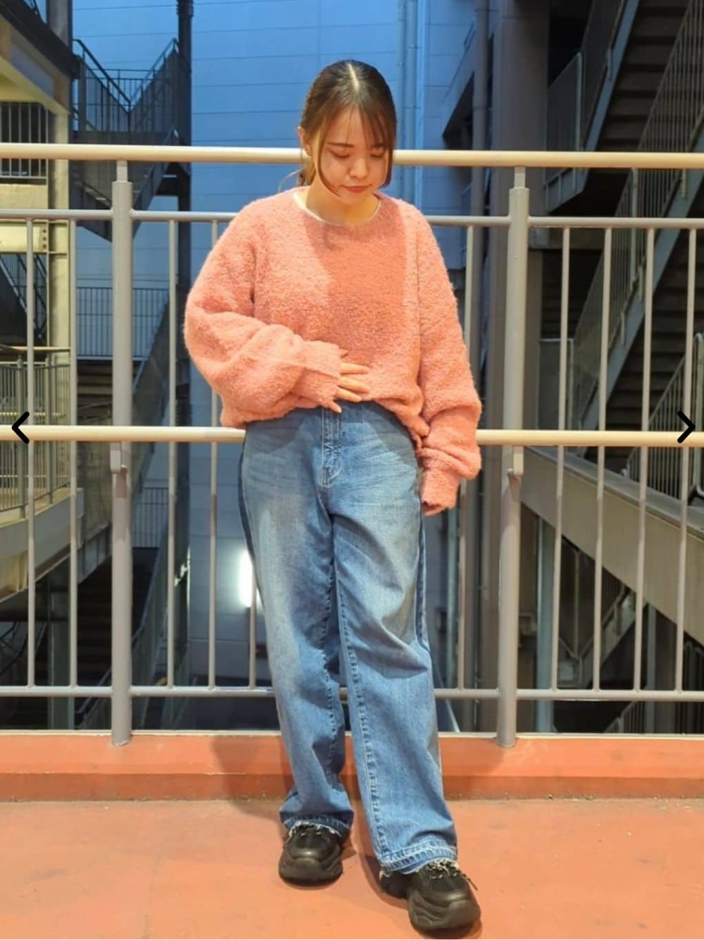 ピンク系のニット/セーター、ブルー系のデニムパンツを着用したレディースの秋コーディネートの1枚目の写真