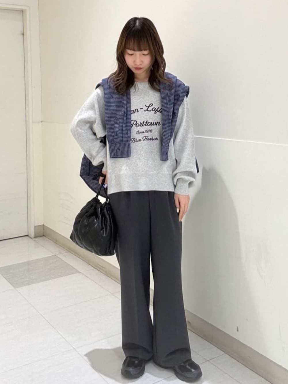 ブラック系のショルダーバッグ、グレー系のニット/セーター、ブルー系のシャツ/ブラウスを着用したレディースの秋コーディネートの1枚目の写真