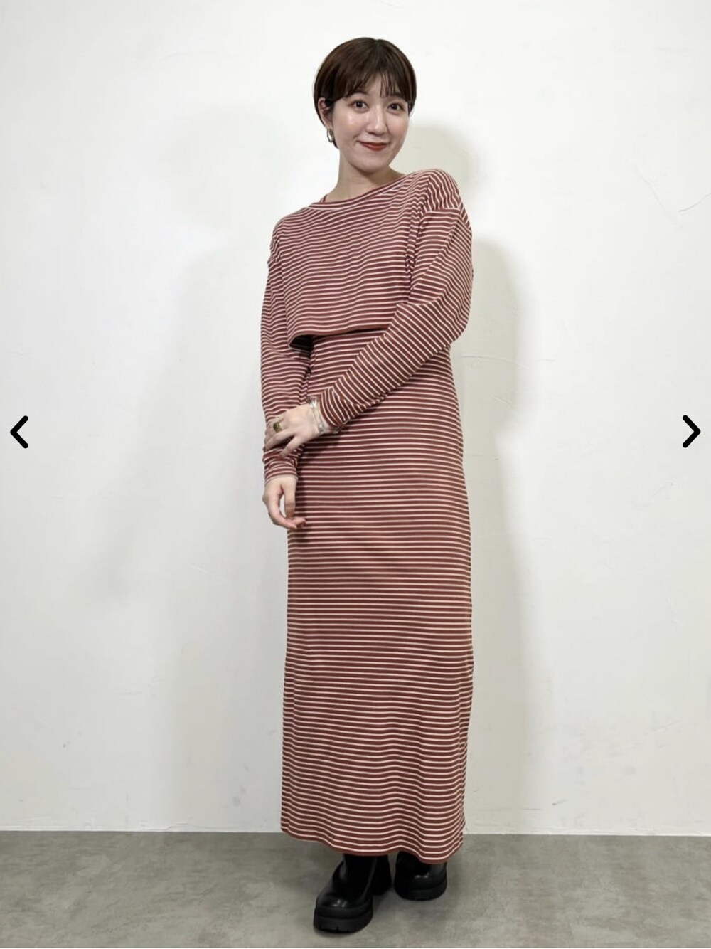 オレンジ系のワンピース、ブラック系のブーツを着用したレディースの夏コーディネートの1枚目の写真