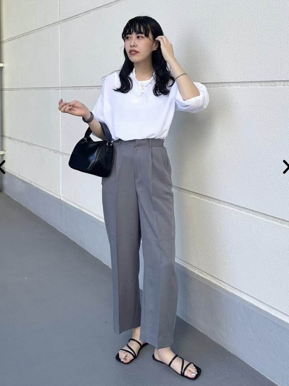 ホワイト系のシャツ/ブラウス、グレー系のスラックス、ブラック系のショルダーバッグを着用したレディースの夏コーディネートの1枚目の写真