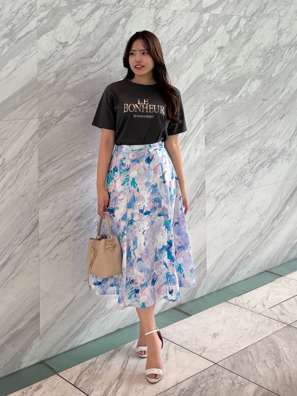 グレー系のTシャツ/カットソー、ピンク系のスカート、ベージュ系のショルダーバッグを着用したレディースの春コーディネートの1枚目の写真
