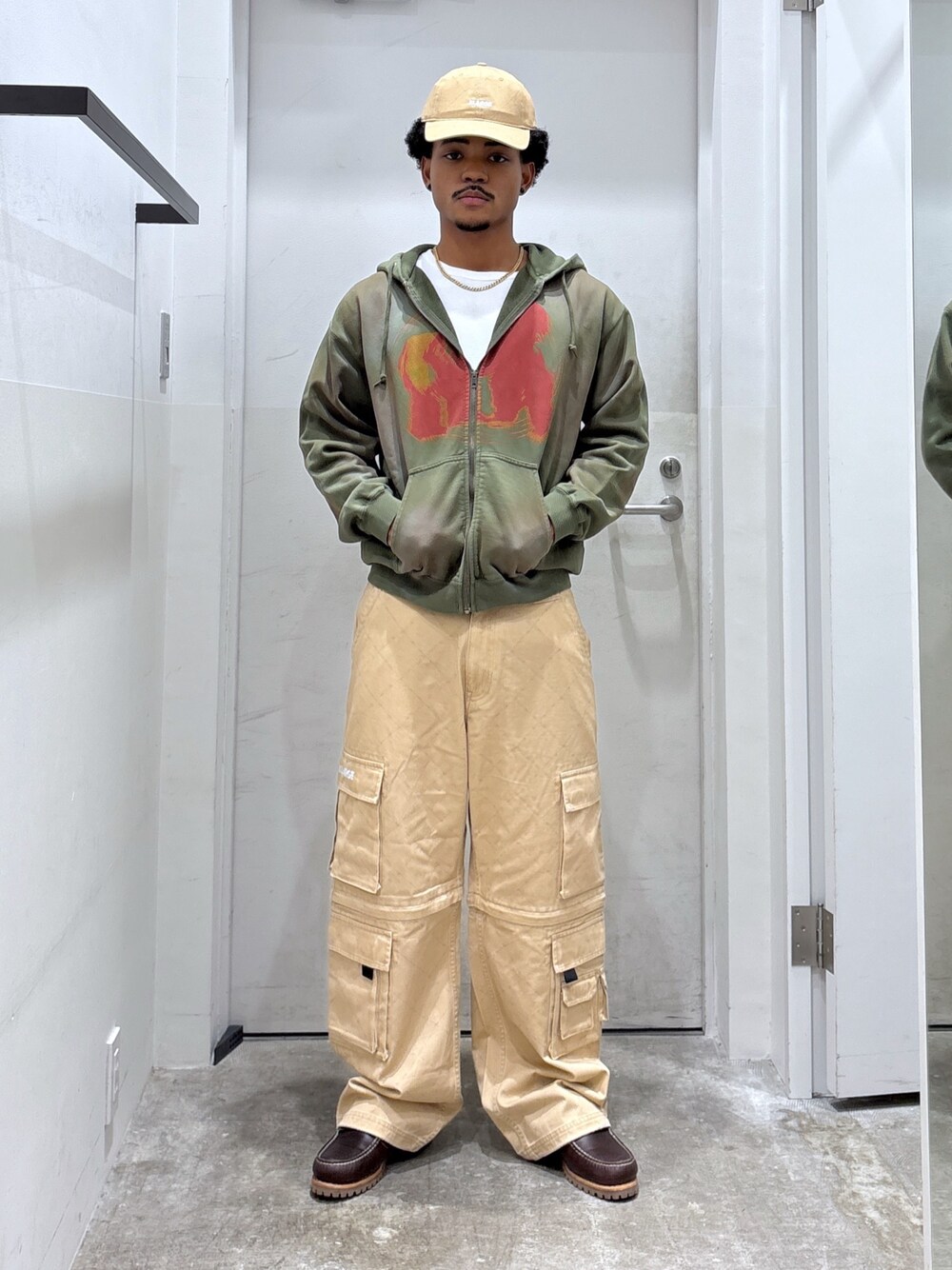 ベージュ系のカーゴパンツ、グリーン系のパーカー、ベージュ系のキャップを着用したメンズの秋コーディネートの1枚目の写真