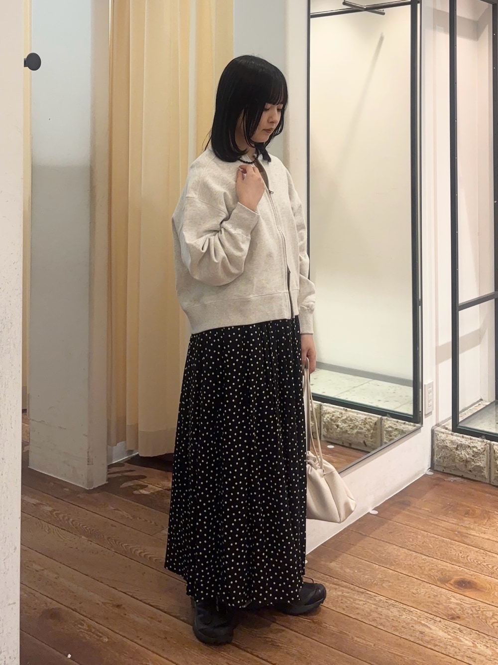 ブラック系のスカート、ホワイト系のショルダーバッグ、ブラック系のスニーカーを着用したレディースの春コーディネートの1枚目の写真