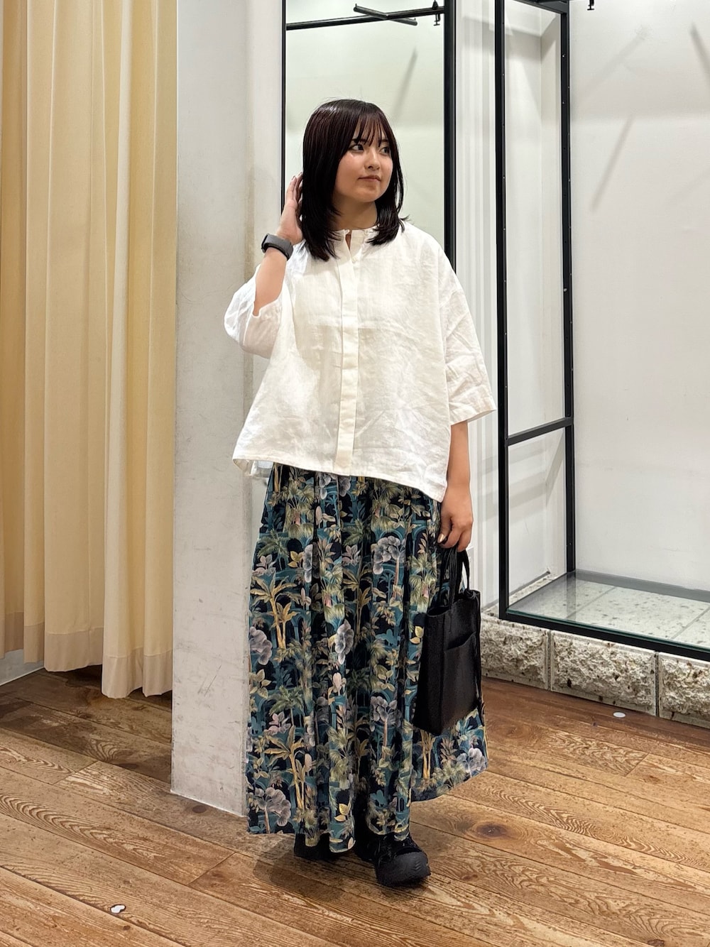 ホワイト系のシャツ/ブラウス、ブルー系のスカート、ブラック系のトートバッグを着用したレディースの夏コーディネートの1枚目の写真