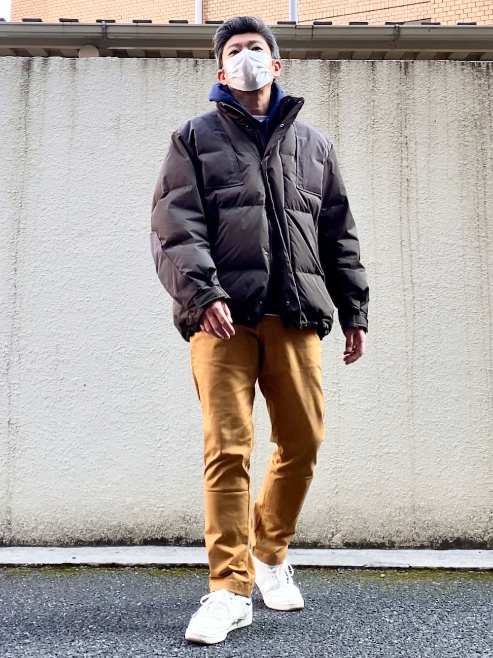 イエロー系のチノパンツ、グリーン系のスニーカー、その他のダウンジャケット/コートを着用したメンズの冬コーディネートの1枚目の写真