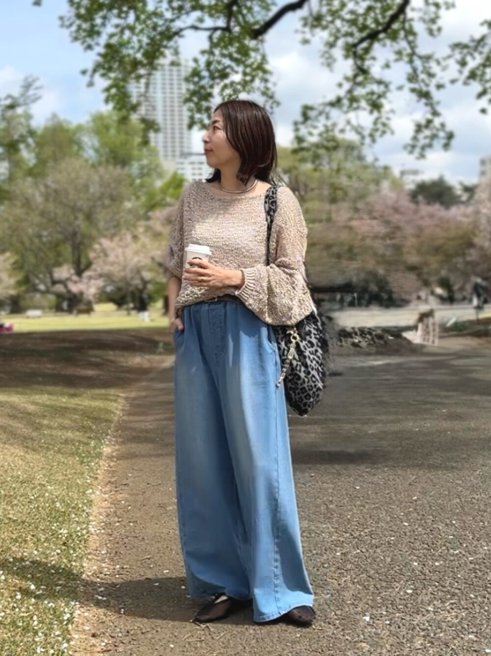 ベージュ系のニット/セーター、ブルー系のデニムパンツ、グレー系のトートバッグを着用したレディースの春コーディネートの1枚目の写真