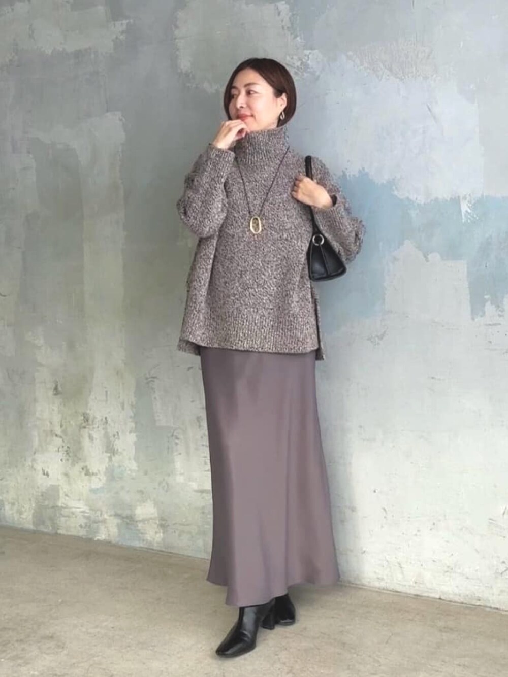ブラウン系のスカート、ブラウン系のニット/セーター、ブラック系のハンドバッグを着用したレディースの秋コーディネートの1枚目の写真