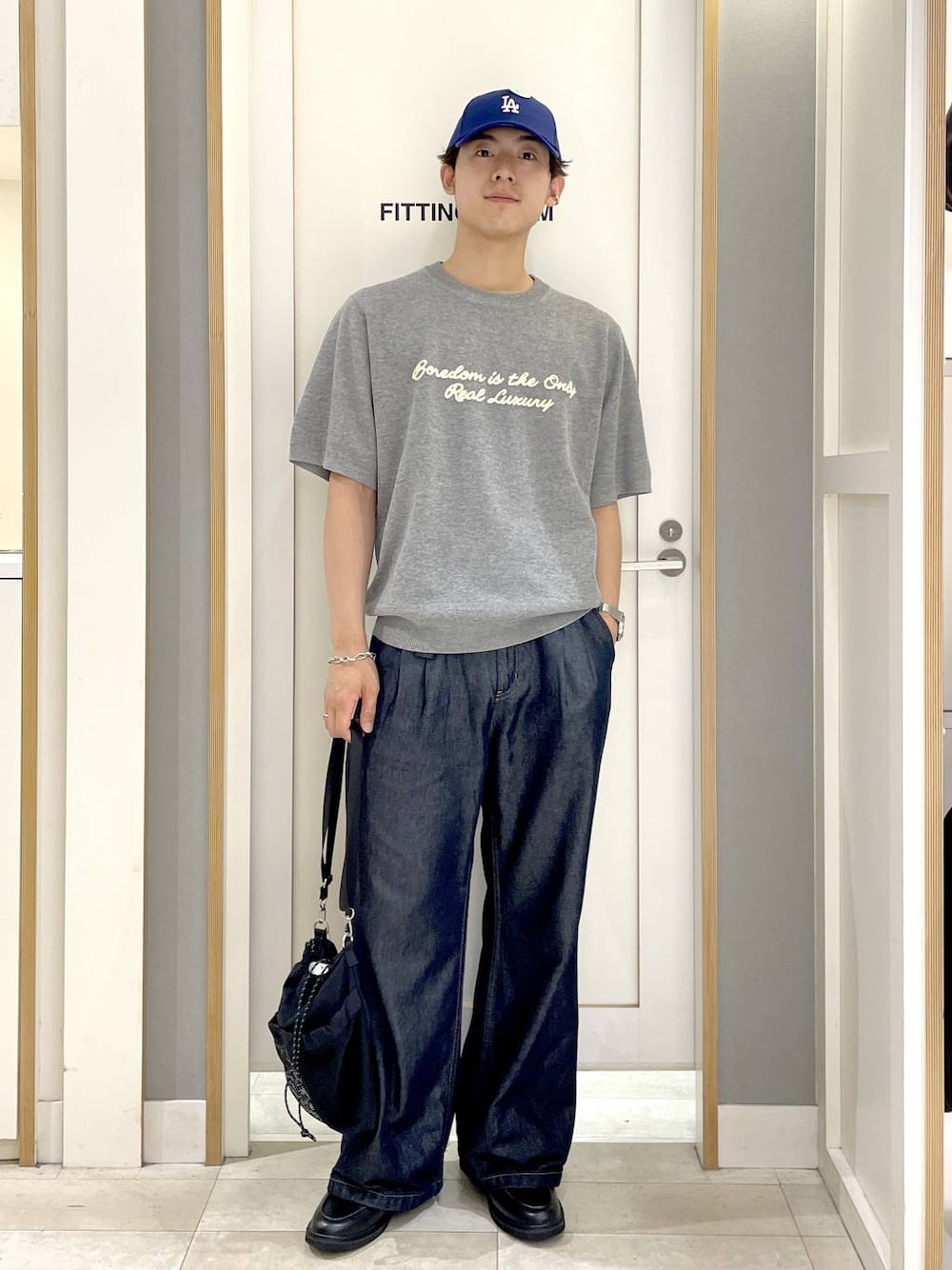 ブラック系のショルダーバッグ、グレー系のニット/セーター、ブルー系のデニムパンツを着用したメンズの夏コーディネートの1枚目の写真