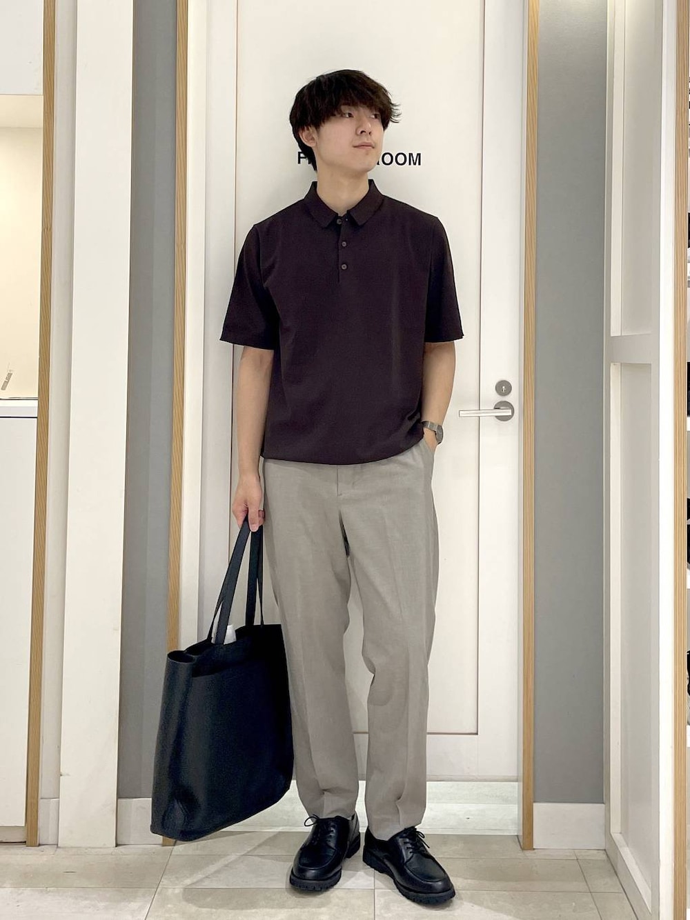 ブラック系のトートバッグ、ブラウン系のスラックス、グレー系のその他シューズを着用したメンズの夏コーディネートの1枚目の写真