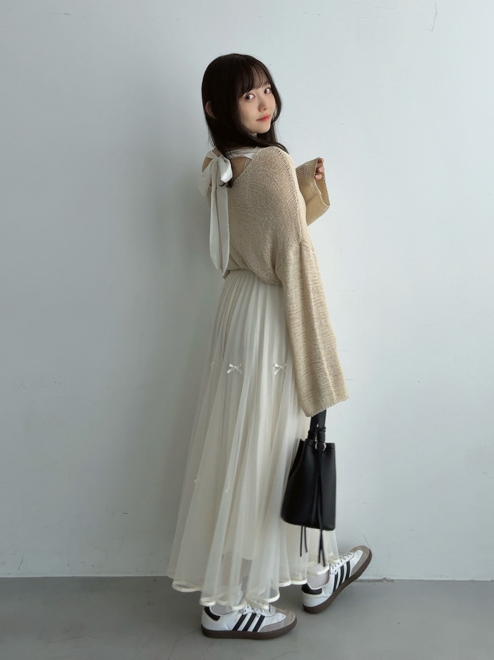 ベージュ系のニット/セーター、ホワイト系のスカート、ブラック系のハンドバッグを着用したレディースの秋コーディネートの1枚目の写真