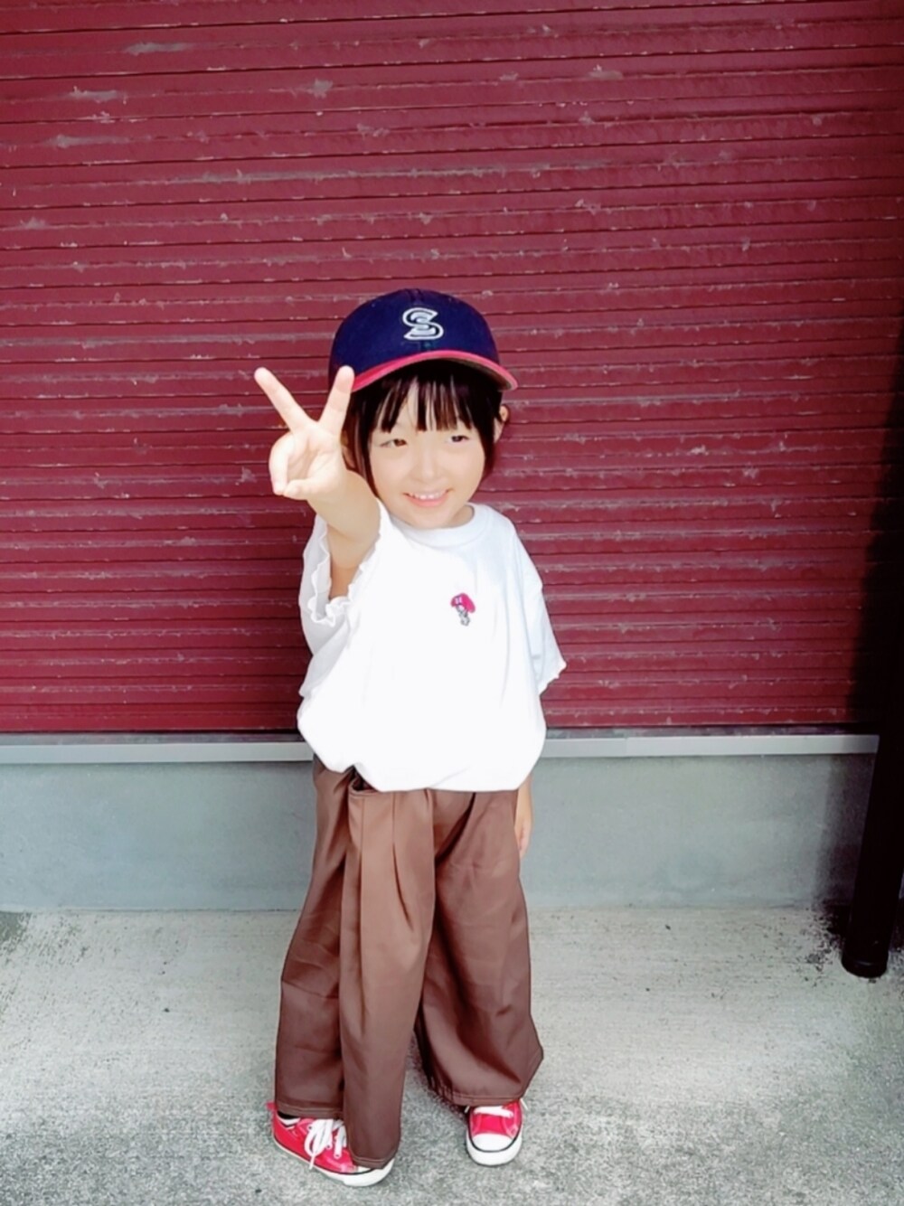 ホワイト系のTシャツ/カットソー、レッド系のスニーカー、ブルー系のキャップを着用したキッズの秋コーディネートの1枚目の写真