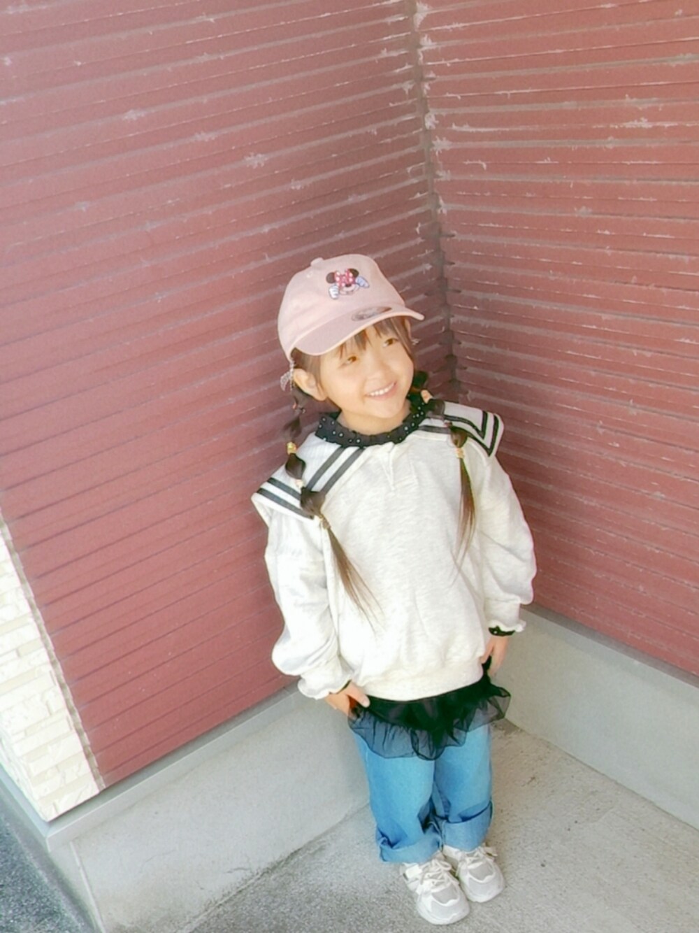 ベージュ系のスウェット、ブラック系のスカート、ブルー系のデニムパンツを着用したキッズの秋コーディネートの1枚目の写真