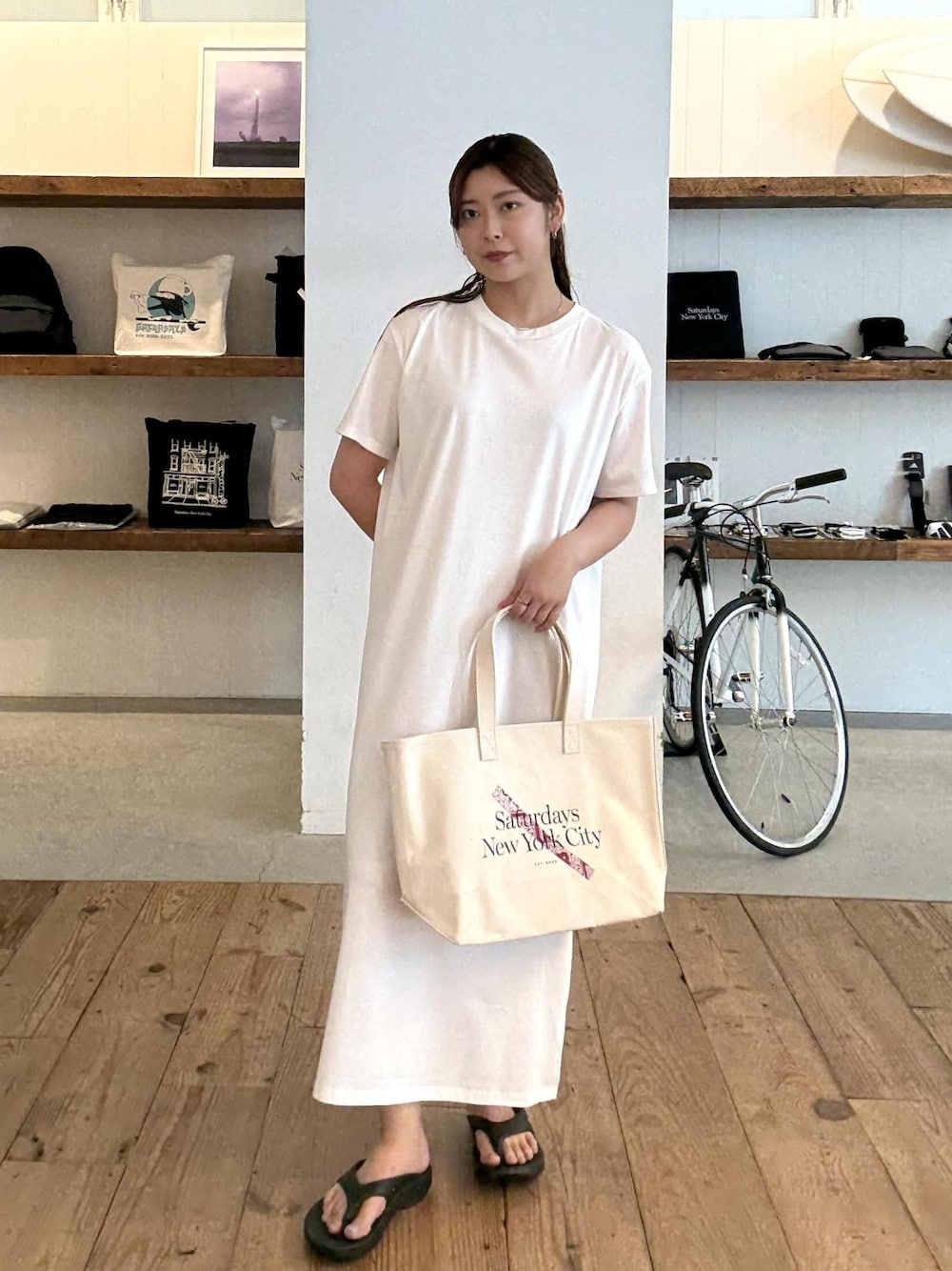 ブラック系のサンダル、ホワイト系のワンピース、レッド系のトートバッグを着用したレディースの夏コーディネートの1枚目の写真