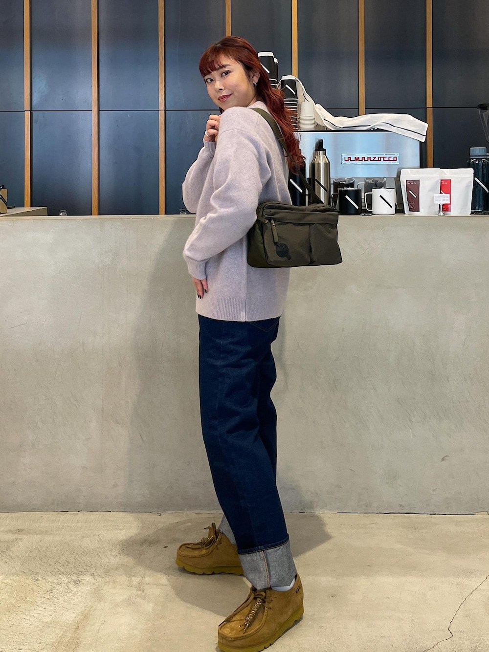 ブルー系のデニムパンツ、グリーン系のショルダーバッグを着用したレディースの冬コーディネートの1枚目の写真