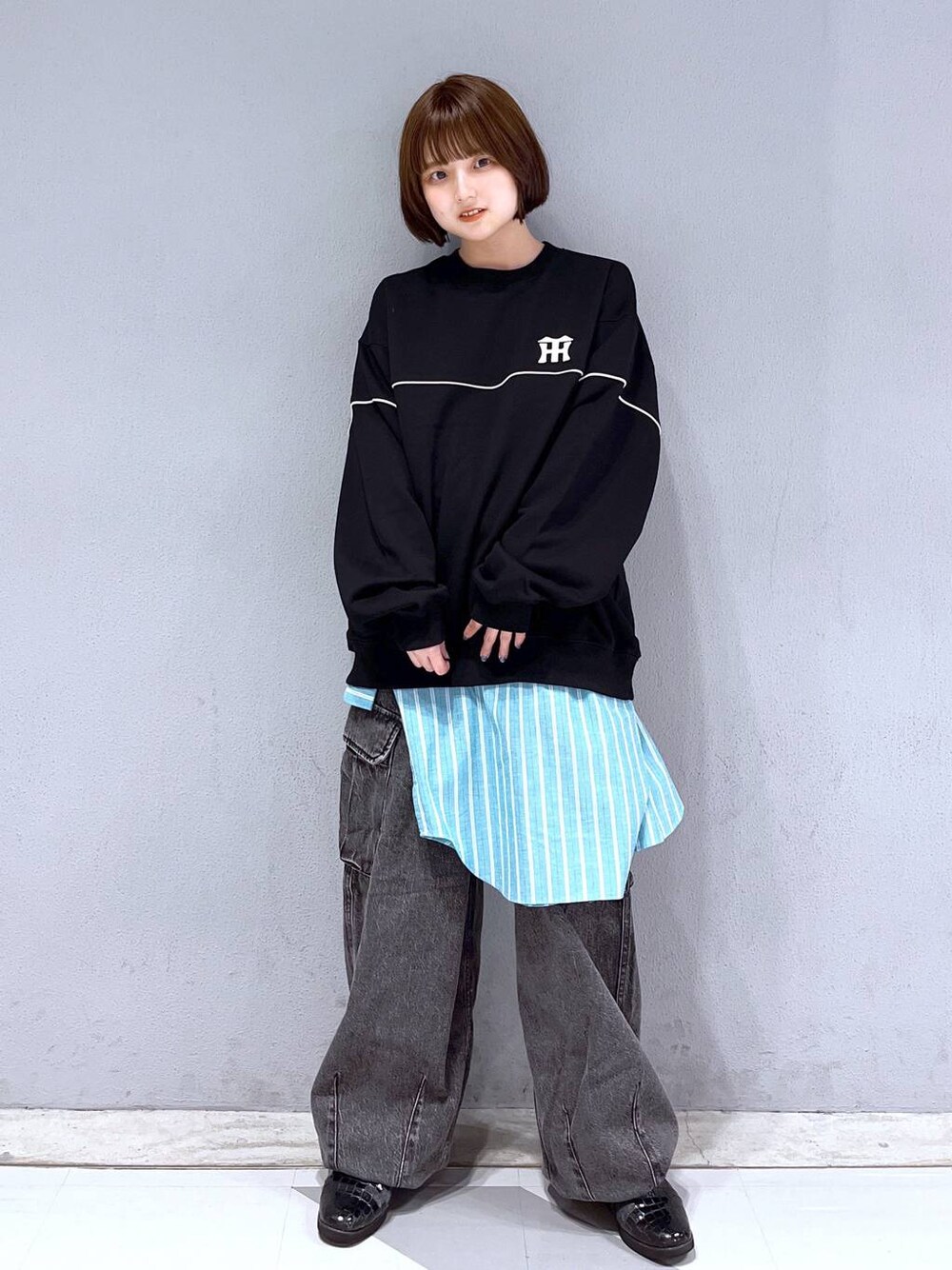 グレー系のデニムパンツ、ブラック系のスウェット、グリーン系のシャツ/ブラウスを着用したレディースの春コーディネートの1枚目の写真