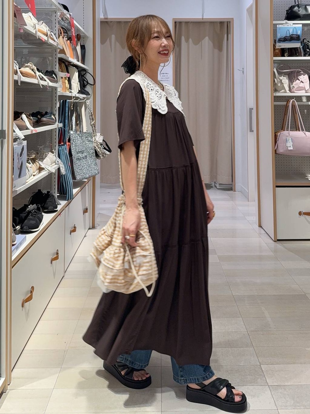 ブルー系のデニムパンツ、ブラウン系のワンピース、ブラック系のサンダルを着用したレディースの夏コーディネートの1枚目の写真