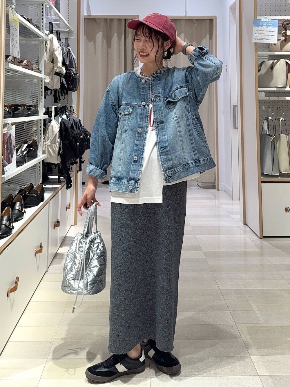 ブラック系のスニーカー、ブルー系のデニムジャケット、シルバー系のハンドバッグを着用したレディースの秋コーディネートの1枚目の写真