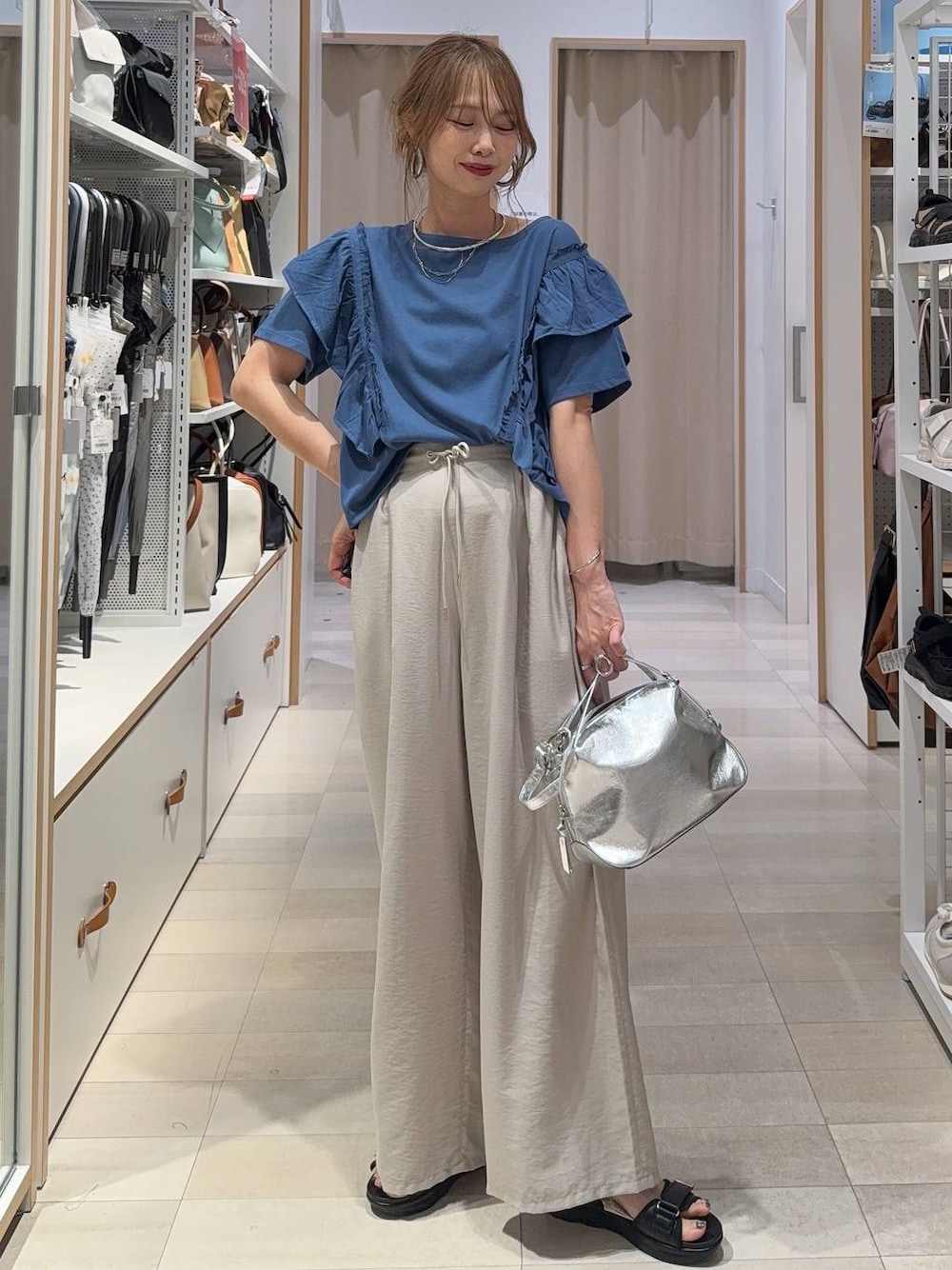 シルバー系のショルダーバッグ、ベージュ系のその他パンツ、ブルー系のTシャツ/カットソーを着用したレディースの夏コーディネートの1枚目の写真