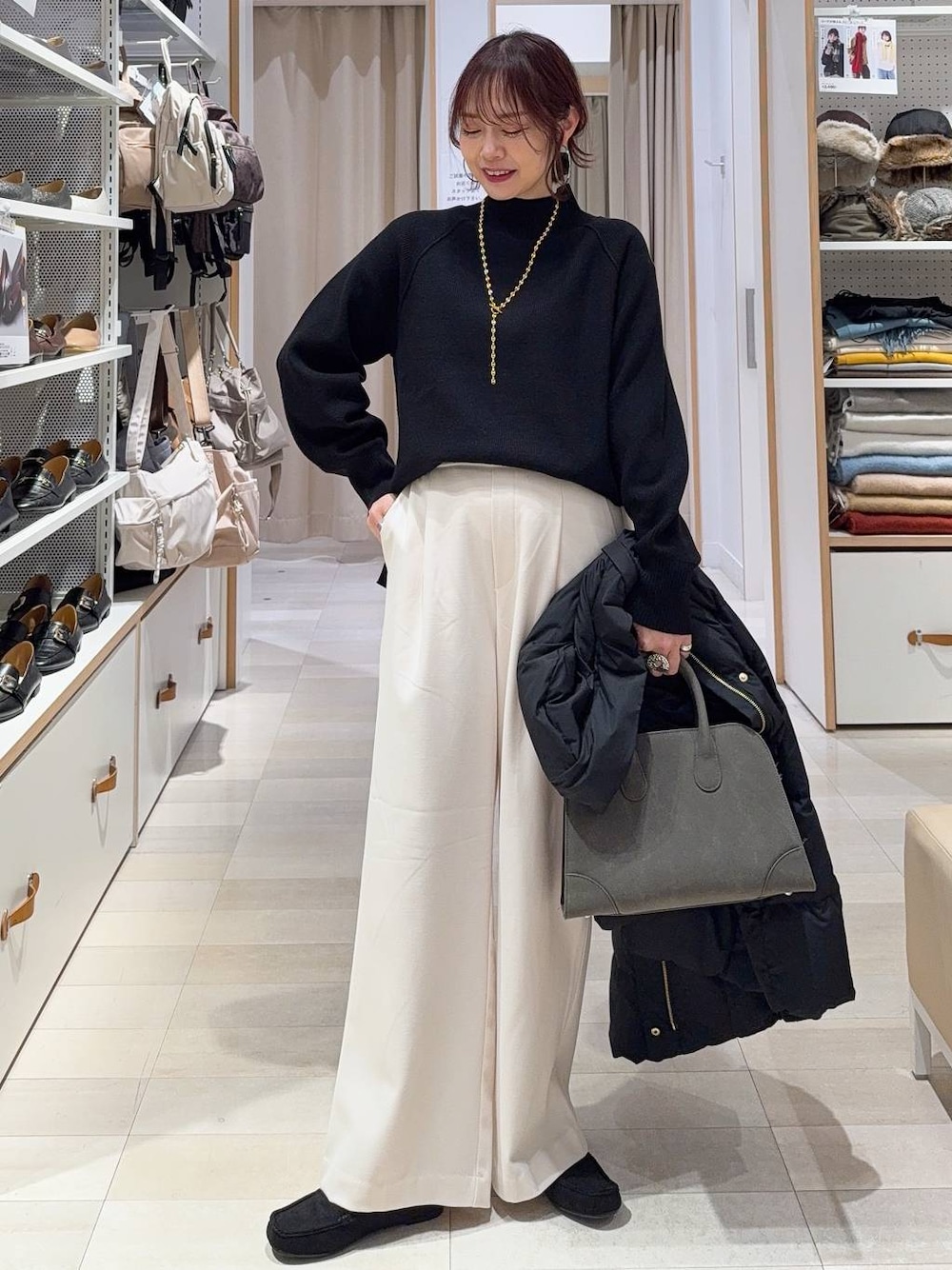 ブラック系のダウンジャケット/コート、グリーン系のショルダーバッグ、ブラック系のニット/セーターを着用したレディースの秋コーディネートの1枚目の写真