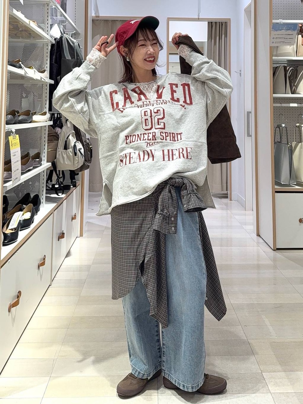 ブルー系のデニムパンツ、ブラウン系のトートバッグ、ブラウン系のシャツ/ブラウスを着用したレディースの秋コーディネートの1枚目の写真