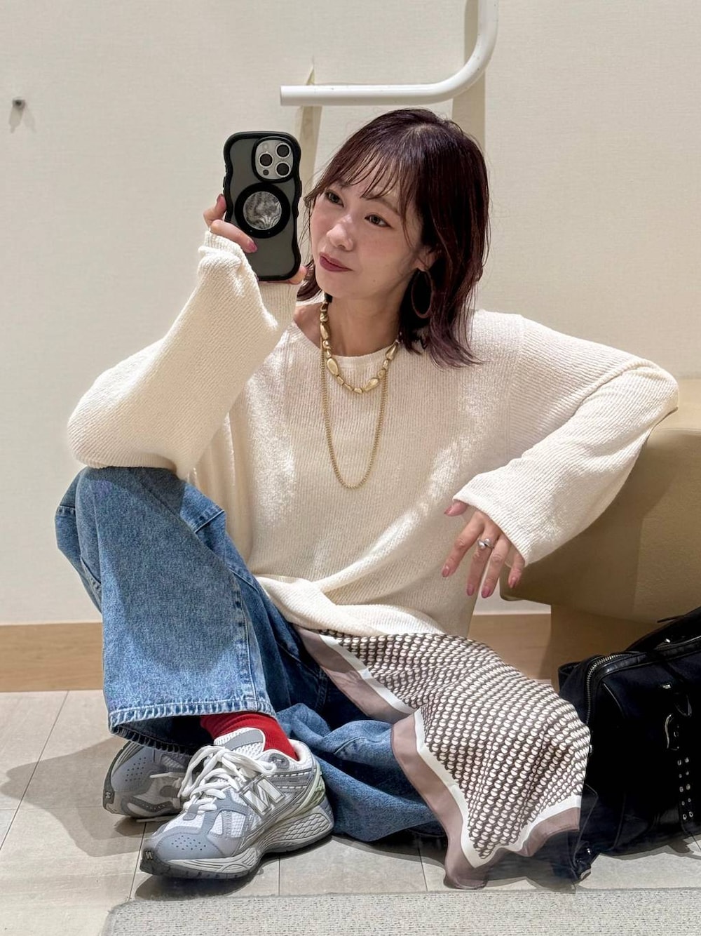 ホワイト系のキャミソール、ブルー系のデニムパンツ、ブラック系のボストンバッグを着用したレディースの秋コーディネートの1枚目の写真