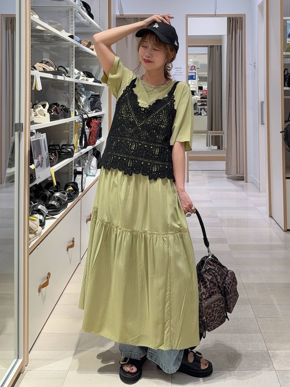 グリーン系のワンピース、ブルー系のデニムパンツ、ブラック系のサンダルを着用したレディースの夏コーディネートの1枚目の写真