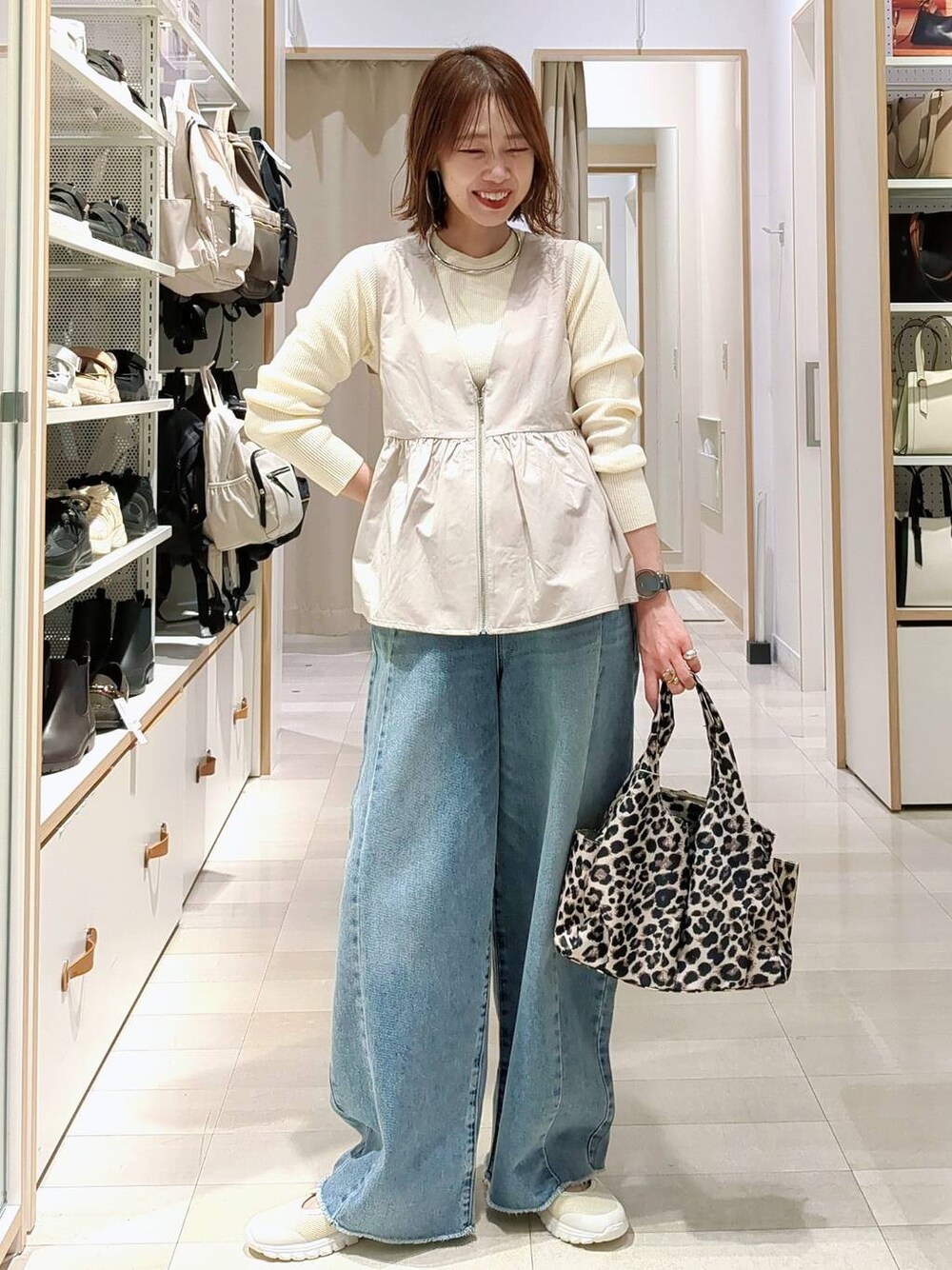 ホワイト系のニット/セーター、ホワイト系のスニーカー、ブルー系のデニムパンツを着用したレディースの春コーディネートの1枚目の写真