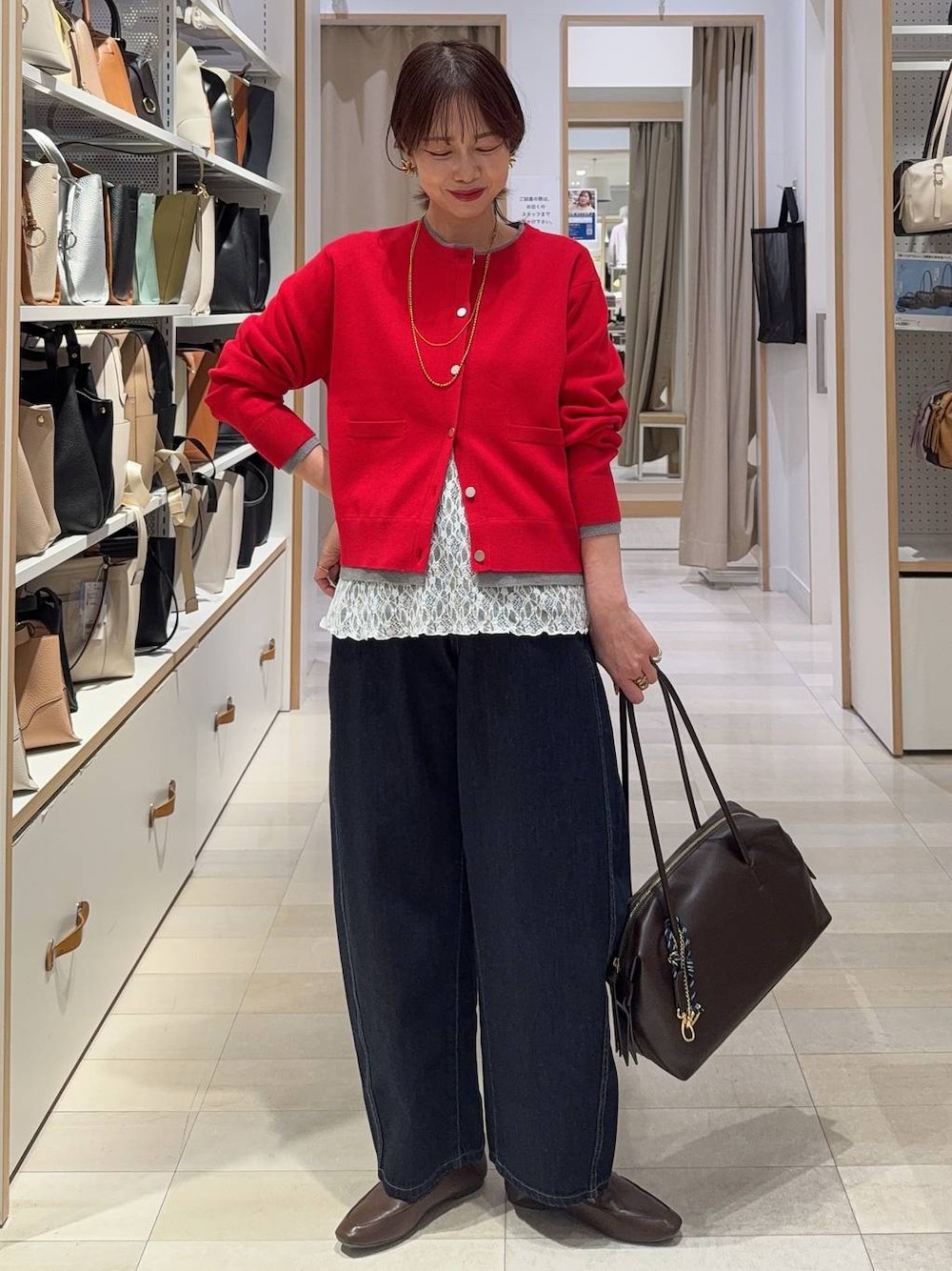 ブラウン系のボストンバッグ、ブルー系のデニムパンツ、レッド系のカーディガン/ボレロを着用したレディースの春コーディネートの1枚目の写真